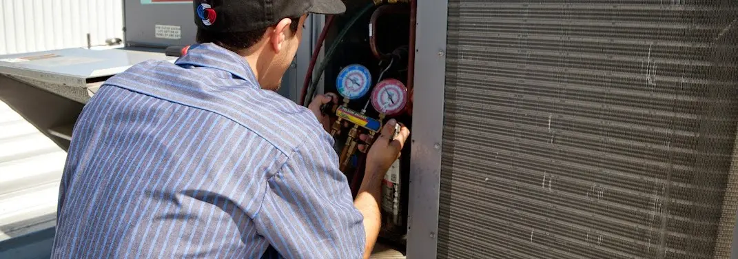 HVAC technician servicing a condenser unit in Mebane