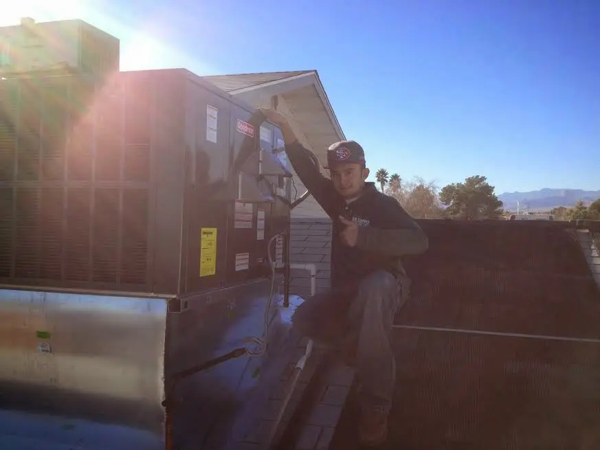 HVAC technician performing AC Tune-Up on a rooftop unit in Mebane